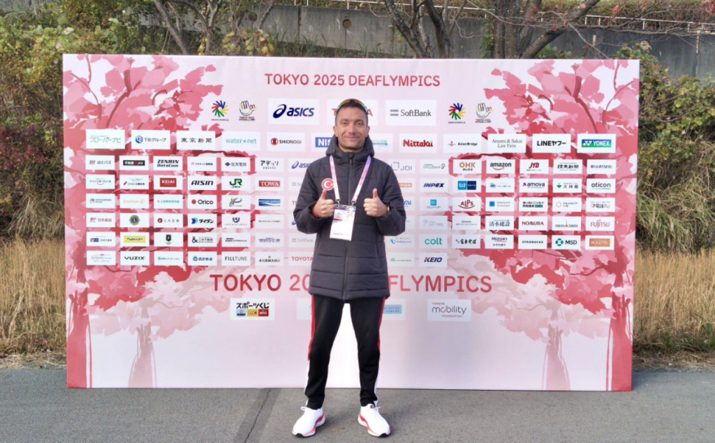 Tokyo 2025 Deaflympics sponsor panosu önünde